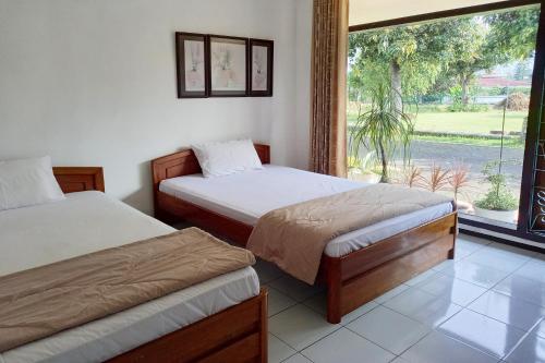 two beds in a room with a large window at Vanda Villa in Batu