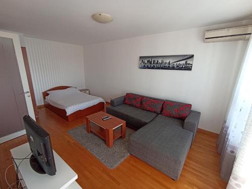 uma sala de estar com um sofá e uma cama em Apartment Tifani em Belgrado