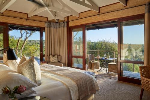 a bedroom with a large bed and a balcony at Kwandwe Private Game Reserve - Ecca Lodge in Grahamstown