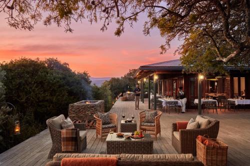 a patio with chairs and tables on a deck at Kwandwe Ecca Lodge in Grahamstown