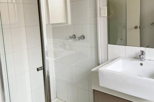 biała łazienka z umywalką i prysznicem w obiekcie Family Home in Riverdale Village Town Tarneit w mieście Tarneit