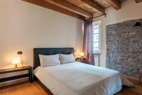 a bedroom with a bed and a stone wall at Residence V in Ponte di Legno