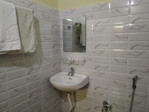 La salle de bains blanche est pourvue d'un lavabo et d'un miroir. dans l'établissement Sundarban Tiger Roar Resort, à Purbbadulki