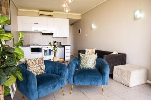 uma sala de estar com duas cadeiras azuis e uma cozinha em Point water front executive apartment em Durban