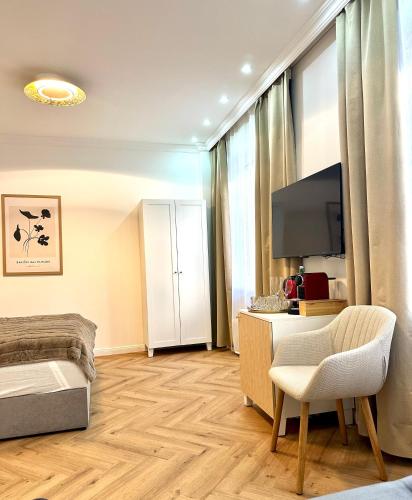 a room with a bed and a television and a chair at MIRABELLE Homes in Salzburg