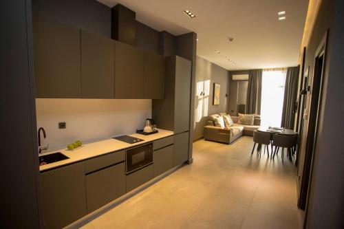 a kitchen with dark cabinets and a living room at Gumbati Apart Hotel in Batumi