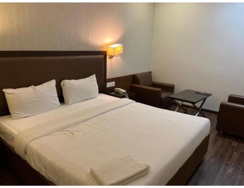 una camera d'albergo con un grande letto con lenzuola bianche di Hotel City Inn, Kakinada, Andhra Pradesh a Kākināda