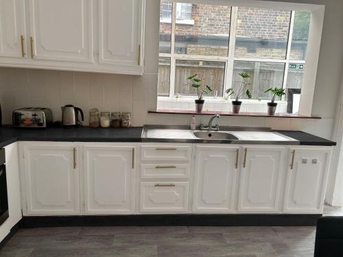 ロンドンにあるBalham, South London Spacious Guest House F2, 6 rooms availableの白いキャビネット、シンク、窓付きのキッチン
