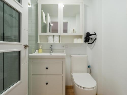 Baño blanco con aseo y lavamanos en Suites Garden Apartamento 14, en Las Palmas de Gran Canaria