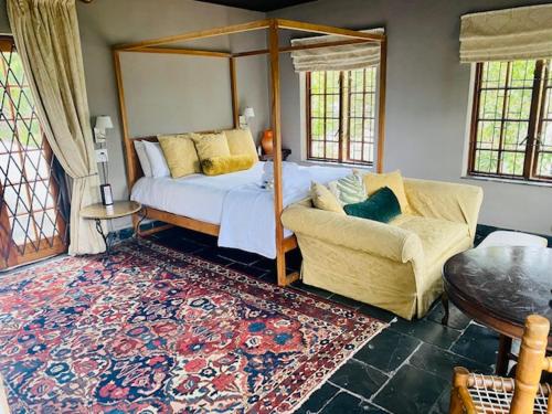 1 dormitorio con cama con dosel y sofá en Boord Guest House, en Stellenbosch
