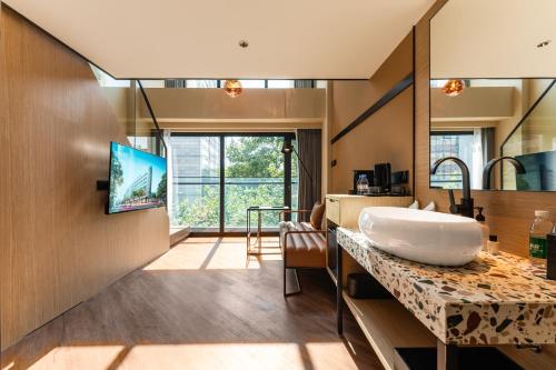 uma casa de banho com um lavatório e uma televisão num balcão em Mia Hotel - Shanghai Xuhui Jiaotong University em Xangai