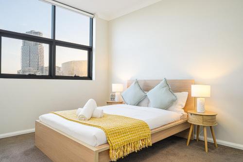 Schlafzimmer mit einem Bett und einem großen Fenster in der Unterkunft Parramatta lovely 2br near station with City view in Sydney