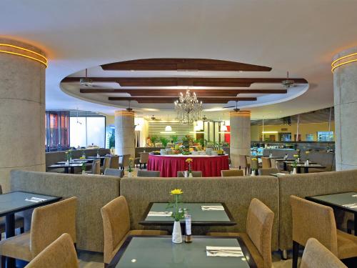 a restaurant with tables and chairs and a chandelier at Kuta Paradiso Hotel in Kuta