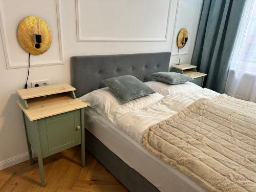 ein Bett mit zwei Kissen darauf mit einem Nachttisch in der Unterkunft morand I Apartments in Salzburg