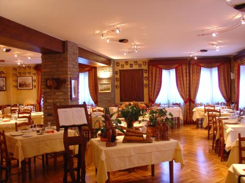a dining room with white tables and chairs at Hotel Dei Camosci in Courmayeur