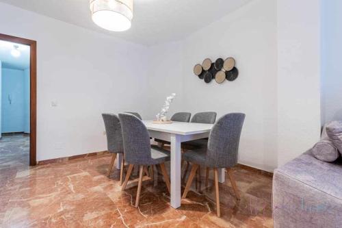 a dining room with a white table and chairs at A estrenar pleno centro, parking in Huelva