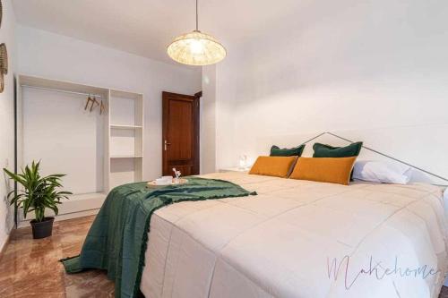 a bedroom with a large bed with green and yellow pillows at A estrenar pleno centro parking in Huelva