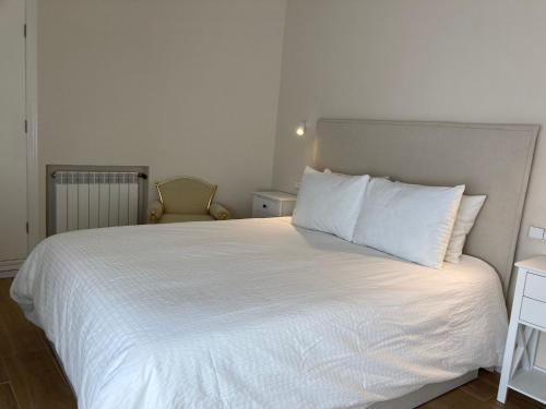 uma cama com lençóis brancos e almofadas num quarto em Ciudad del Encaje 3 em Almagro