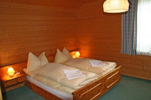 Cama en habitación de madera con 2 almohadas en Liftgasthof Appartements en Zauchensee