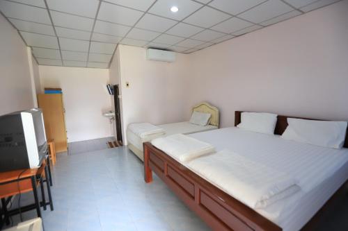 a bedroom with two beds and a television in it at banrainaifun in Ban Pong Chang Thaeng