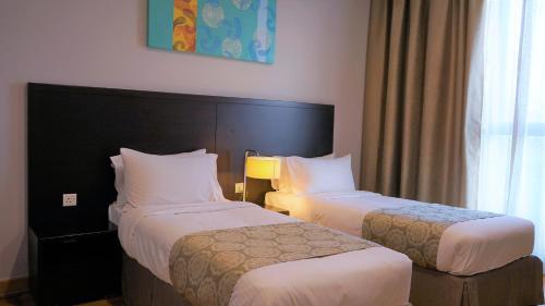 a hotel room with two beds and a window at Trinidad Suites Johor, Trademark Collection by Wyndham in Nusajaya