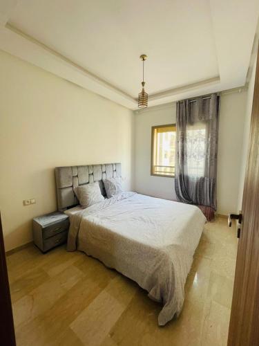 Un dormitorio con una cama grande y una ventana en Cosy appartement, en Nouaceur