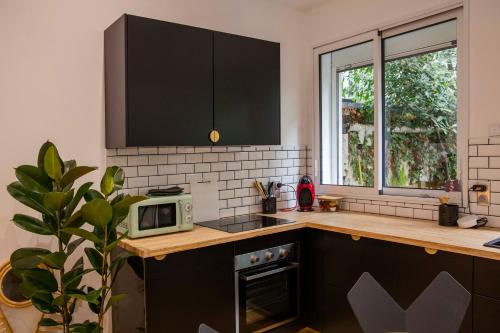 eine Küche mit schwarzen Schränken und einer Mikrowelle in der Unterkunft La Petite Échoppe - Chartrons in Bordeaux