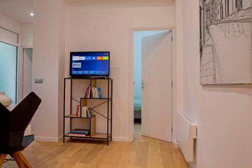 a living room with a television and a book shelf at La Petite Échoppe - Chartrons in Bordeaux