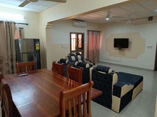 ein Wohnzimmer mit einem Tisch und Stühlen sowie einem TV in der Unterkunft Sarada Hôtel in Ouagadougou
