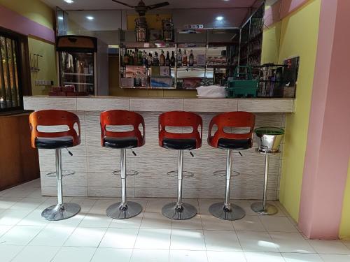 a bar with three red bar stools in a restaurant at Sarada Hôtel in Ouagadougou