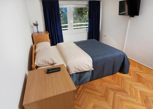 a bedroom with a bed and a table with a remote control at Apartman Vrancic in Banja Luka