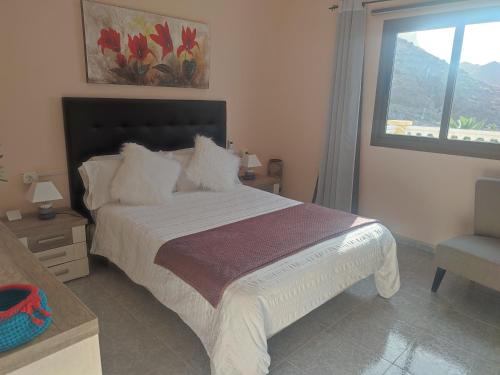 1 dormitorio con 1 cama con ventana y silla en Casa Rural La Vega en Alojera