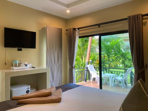 a bedroom with a bed with a television and a balcony at Serene Lanta Resort in Ko Lanta