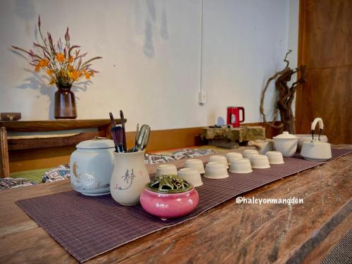 Kon Von Kla的住宿－Halcyon Homestay Mang Den，木桌上的一组白色花瓶
