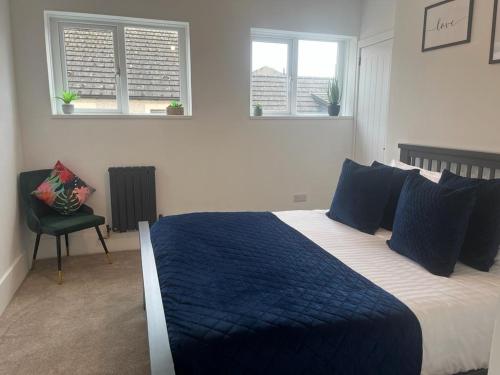 a bedroom with a bed and a chair and two windows at The Boyd - Coorie Doon in Prestwick