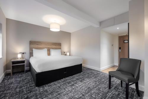 Habitación de hotel con cama y silla en The Stones Hotel, en Salisbury