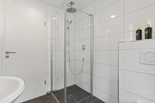 uma casa de banho branca com um chuveiro e um lavatório. em ma suite - Augsburg - Lechhausen em Augsburg