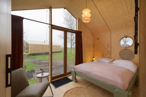 ein Schlafzimmer mit einem Bett und einem großen Fenster in der Unterkunft Rufus aan het water in Broek