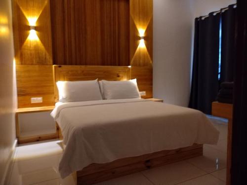 a bedroom with a large bed with a wooden headboard at FUNDUQ AL BUSYRA in Pantai Cenang