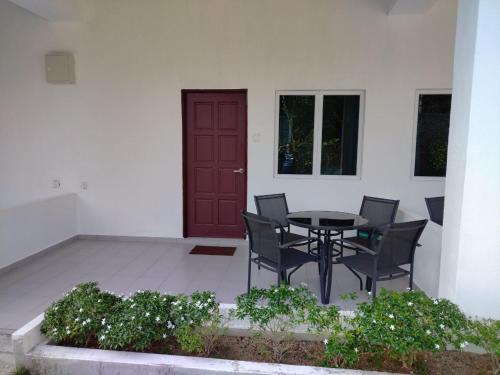 a patio with a table and chairs and a red door at FUNDUQ AL BUSYRA in Pantai Cenang