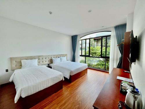 a bedroom with two beds and a large window at Ban Me Central Hotel 2 in Buon Ma Thuot