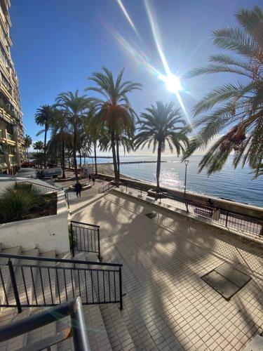 a walkway next to the water with palm trees at Marbella Beach Front Edificio Mayoral Centro Ciudad y Primera Línea Playa Muy Amplio y Espacioso in Marbella