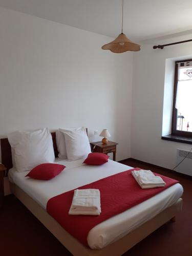 ein Schlafzimmer mit einem großen Bett mit roten und weißen Kissen in der Unterkunft Résidence Les Clarines ( by Popinns ) in Les Rousses