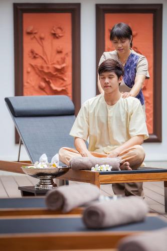 a woman standing behind a man sitting on a table at Huernnana Boutique Hotel in Phrae