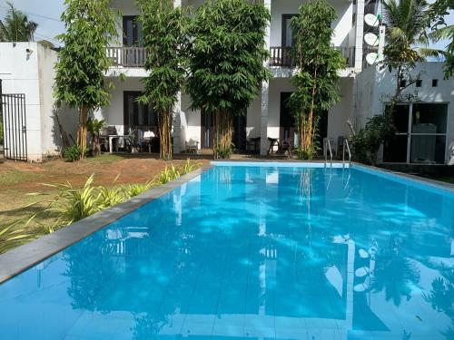 a blue swimming pool in front of a building at KITHULA Boutique Hotel in Hikkaduwa