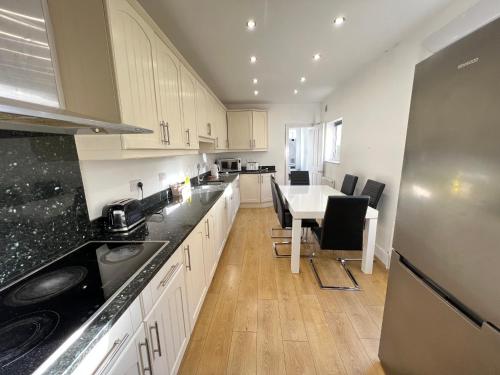 a kitchen with white cabinets and a table with chairs at Lovely 5 Bed house in Medway sleeps 12 in Gillingham