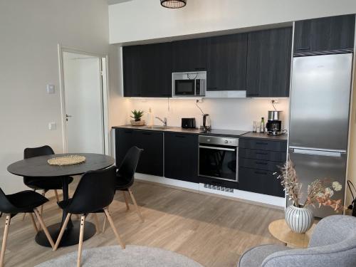 a kitchen with black cabinets and a table and chairs at Beautiful loft apartment with glazed balcony in Tampere
