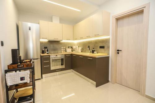 Modern and Luxury apartment في أثينا: مطبخ صغير مع دواليب بيضاء وثلاجة