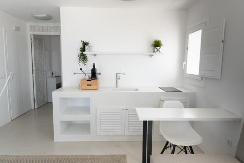 a white kitchen with a white counter and a table at Lemon Tree Houses in Áno Meriá