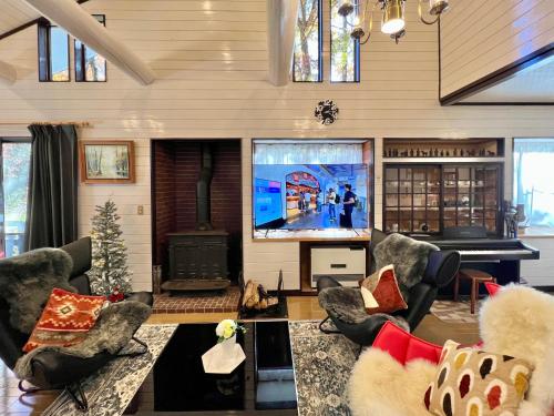 a living room with couches and a tv and a piano at 虹の街22 #Nature Escape BBQ in Kita-karuizawa
